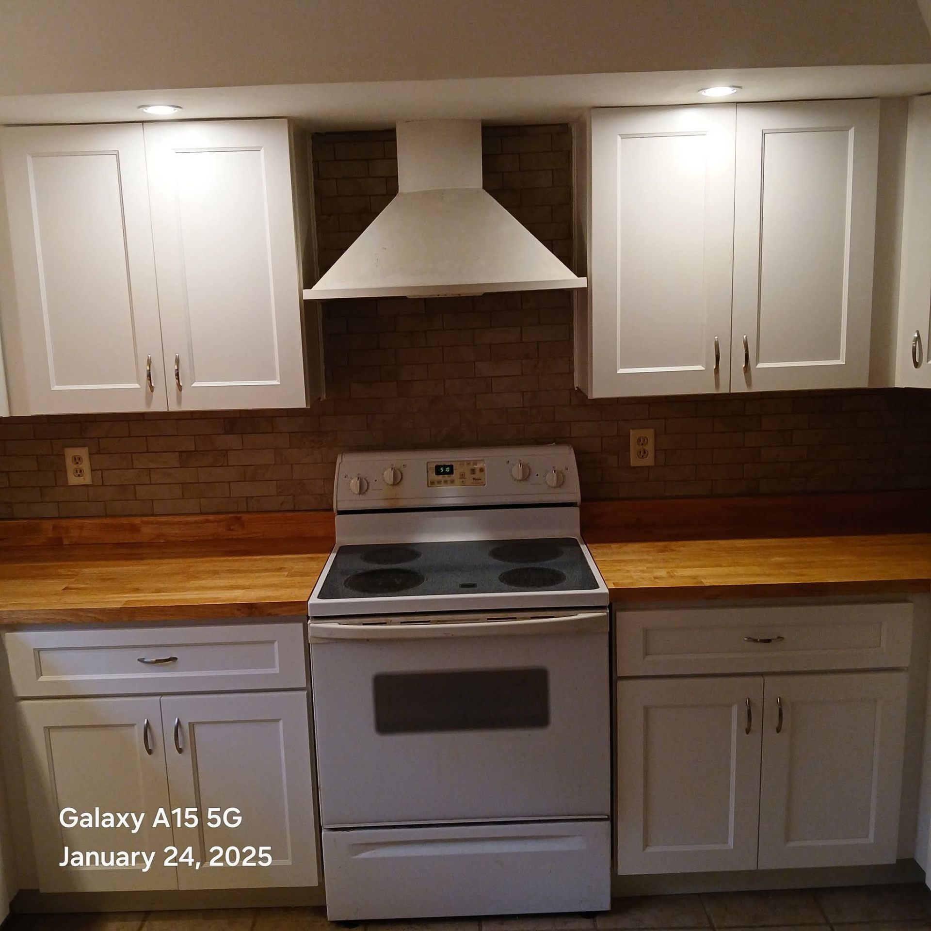 Complete kitchen remodel with white cabinets, brick backsplash, and wood countertops