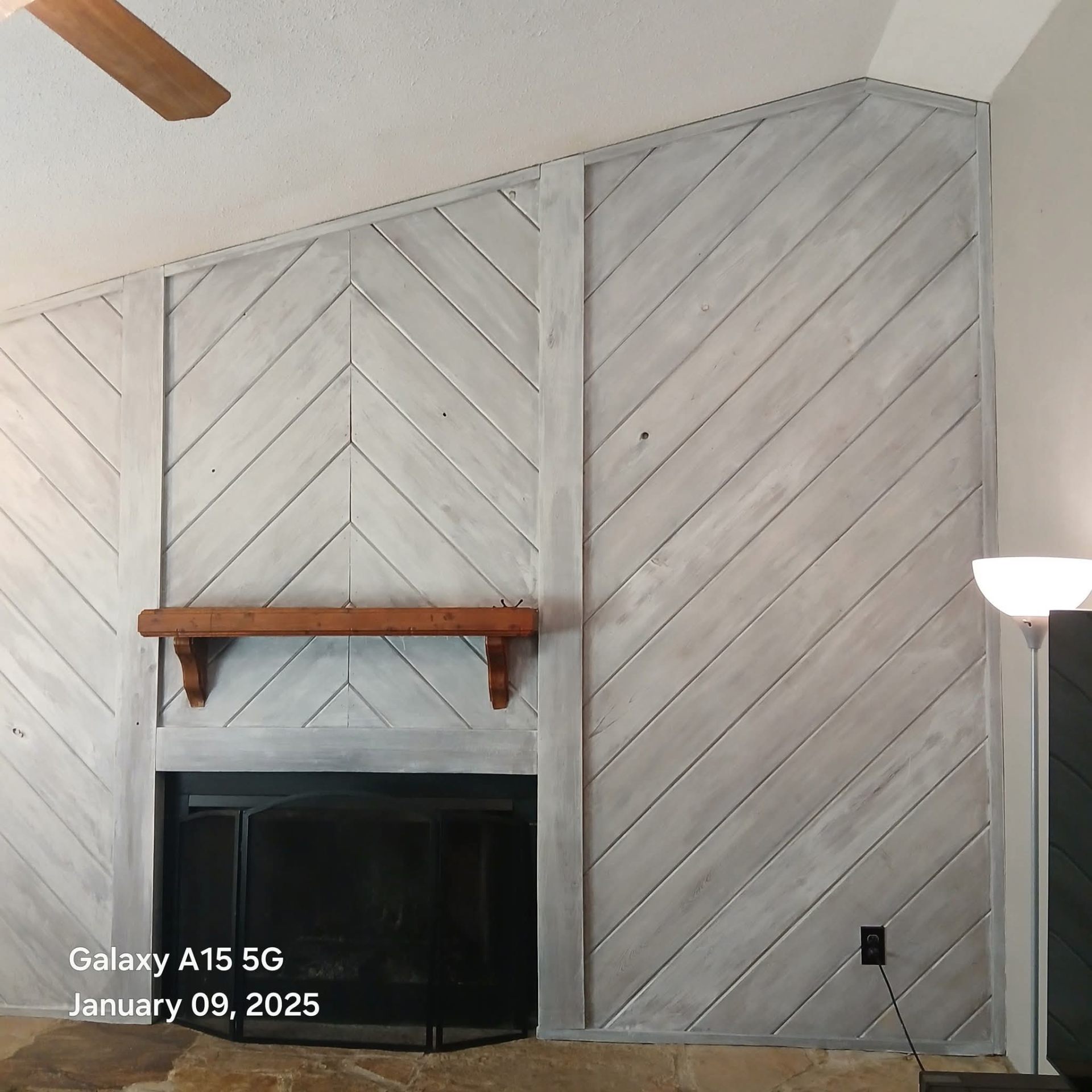 Stunning herringbone wood pattern accent wall around fireplace with custom mantel